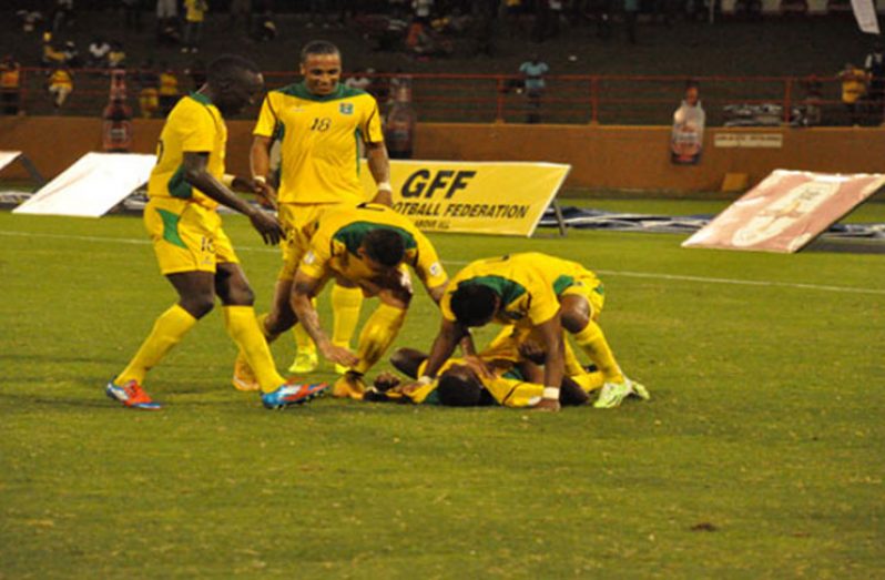 Flash back to 2015! Guyana’s Pernell Schultz (on the ground) is swarmed by Walter Moore (right), (L-R) Joshua Brown, Neil Danns and Matthew Briggs after scoring his second goal against Grenada. (Delano Williams photo)