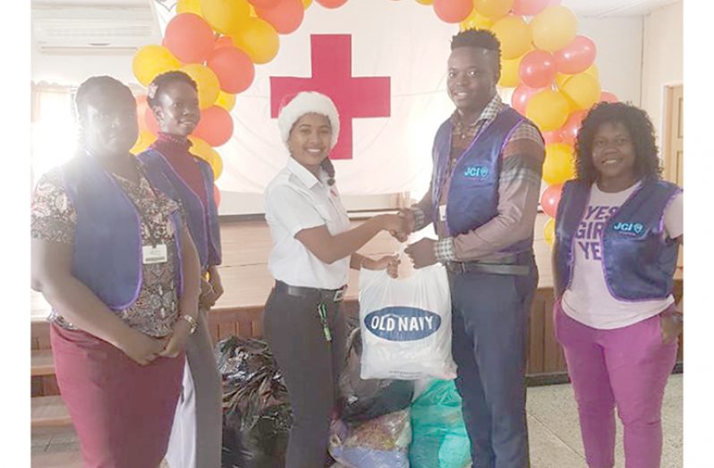 Junior Chambers (JCI) (Guyana) President Kevin Cornette and other members of JCI (Guyana) make a contribution to a representative of the Guyana Red Cross Society