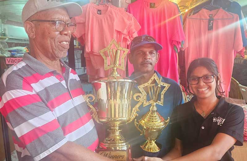 Trophy Stall’s Jennifer Ramdohar hands over the winning and runners-up trophy to Frederick Halley. At centre is Seeraj Bhimsain.