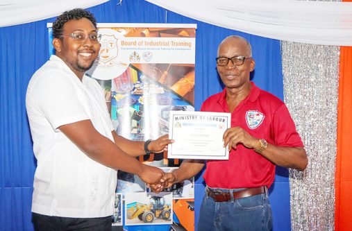 A graduate collects his certificate from Minister of Labour, Joseph Hamilton (BIT photo)