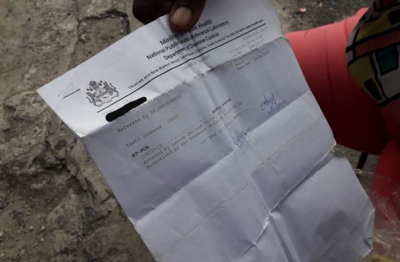 Joy holds up her negative PCR test result for COVID-19 which she received just before leaving the hospital