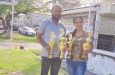 Juliana Rikhee, representative of Trophy Stall Berbice poses with coordinator Abel Seetaram with some of the trophies which will be up for grabs