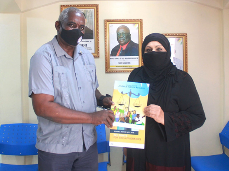Home Affairs Minister, Robeson Benn, receives the Juvenile Justice booklets from Chairman of the Rights of the Child Commission, Aleema Nasir