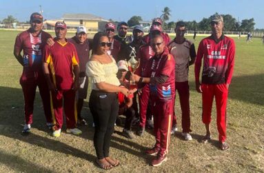 The victorious Parika Defenders captain Kenrick Persaud collects the winning trophy from Maria Pinto