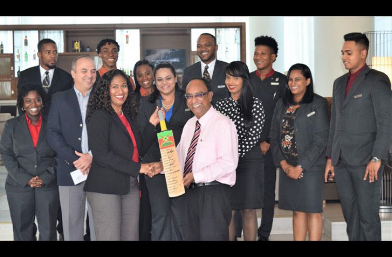 Marriott's Director of Sales Davie Leona Sukdeo collects the bat from Omar Khan while other staff members shares the moment.