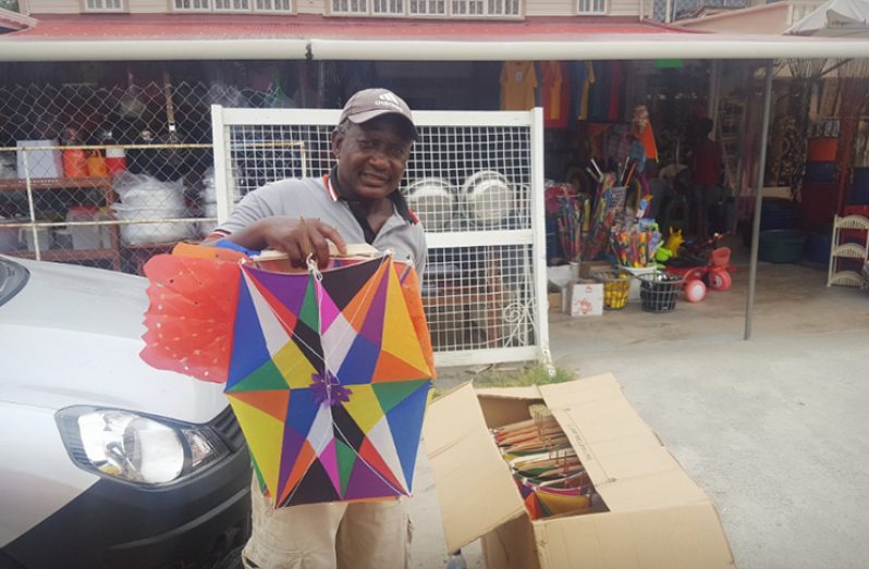 A kite maker displaying his kites at the Anna Regina Market