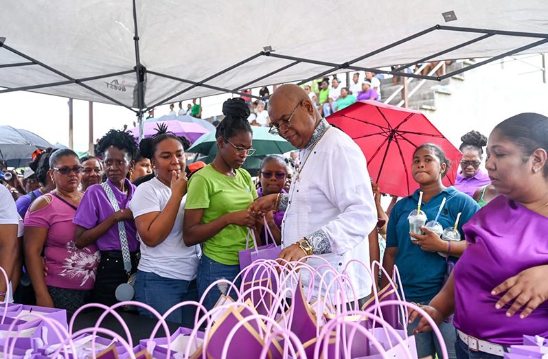 Minister of Public Works Bishop Juan Edghill sharing tokens to women in Kwakwani, Region 10