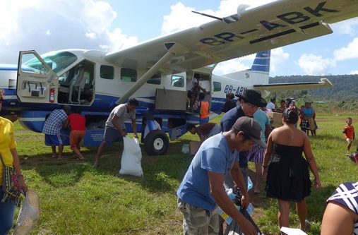 Residents of Chenapau offload supplies from the BK AIR plane
