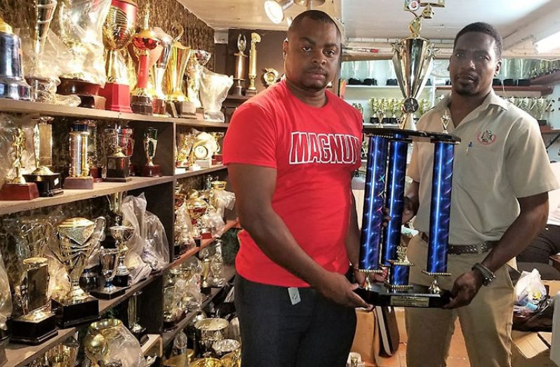 Brand Coordinator for Magnum Tonic Wine, Edison Jefford (left) hands over one of the trophies to LABA President, Lawrence Simon for their Division I Basketball League.