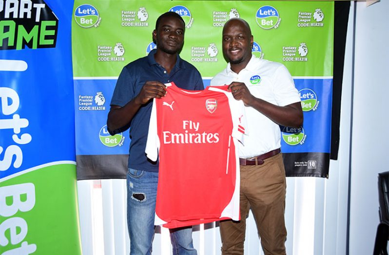 Let’s Bet Sports Brand Ambassador Rawle Toney (right) presents week one Fantasy League winner, Delroy McIntosh, with his Arsenal jersey. (Adrian Narine photo)