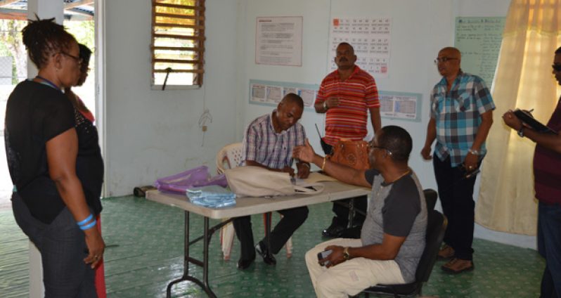Police ‘A’ Division Commander Clifton Hicken, seated, makes a point when he made a visit to the Caledonia/Good Success NDC. Listening are elections workers, left, and other senior police officers who accompanied him