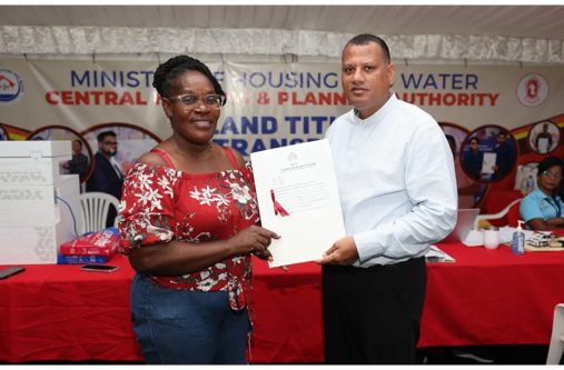 Minister of Housing and Water Collin Croal presents a land title to a recipient