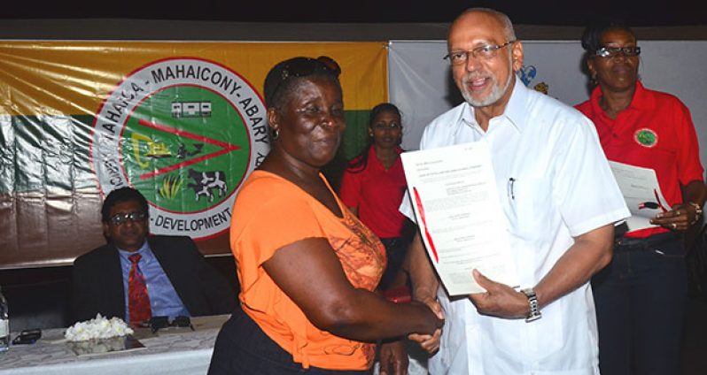 President Donald Ramotar hands over one of over 100 leasehold titles that were distributed last Friday at Bath Settlement, Region 5. In the background is the AG and Minister of Legal Affairs, Mr. Anil Nandlall and MMA officials (Photo by Adrian Narine)