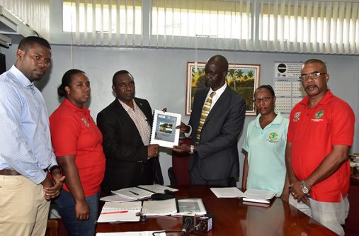 Lands FAO Representative Rueben Robertson presenting a copy of the proposed project document to Guyana Lands and Surveys Commissioner Trevor Benn, in the presence of Manager of the Surveys Division, Rene Duesbury and the Commission’s Legal Advisor, Yolanda Lamott on the right and the Senior Land Administration Officer, Jewel Cheong and Policy Analyst, Durwin Humphrey, on the left.