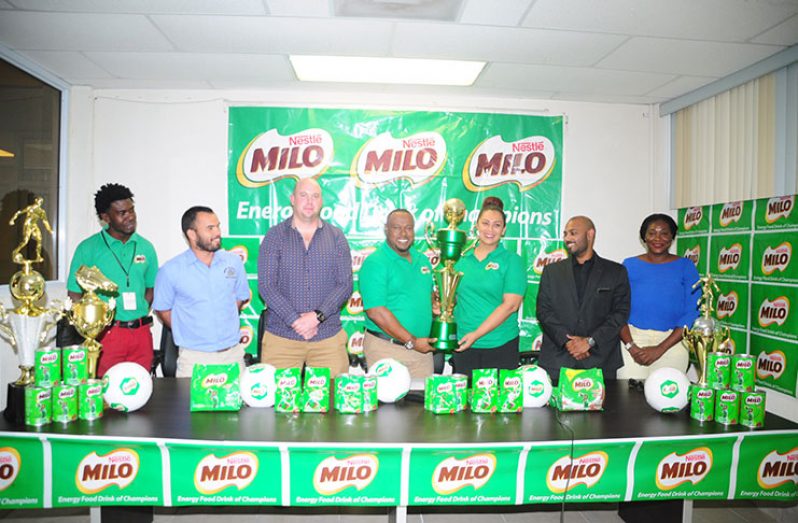 From left: Petra executive Mark Alleyne, Ministry of Education’s Nicholas Fraser and GFF Technical Director Ian Greenwood watch Petra co-Director Troy Mendonca collect the winning trophy from Milo Brand Manager Christel Van Sluytman. Executive Officer Jonathan Beepat and other executives look on. (Delano Williams photo)