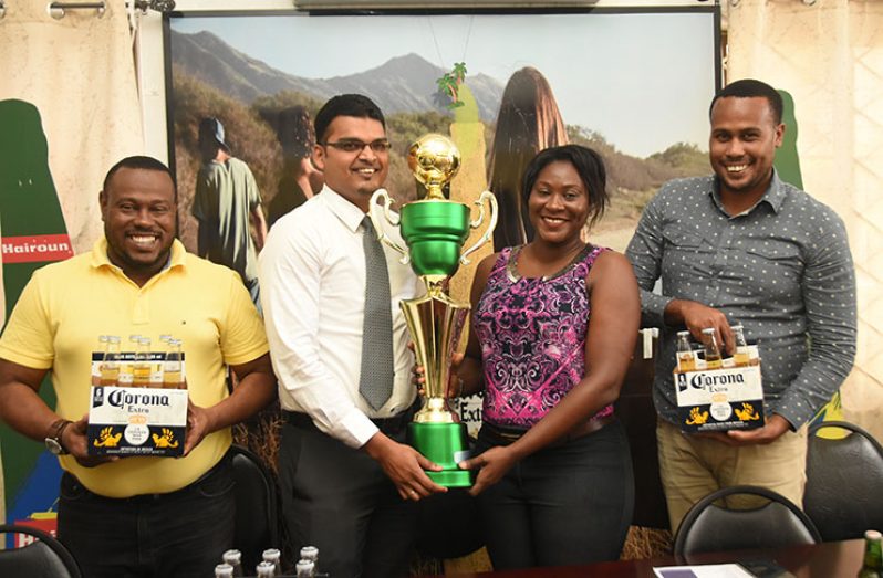 Sales Manager Rishi Rampersaud hands over the trophy to Petra representative Jacklyn Boodie in the presence of co-director Troy Mendonca (left) and Corona Brand Manager Marvin Wray (extreme right). (Adrian Narine photo)