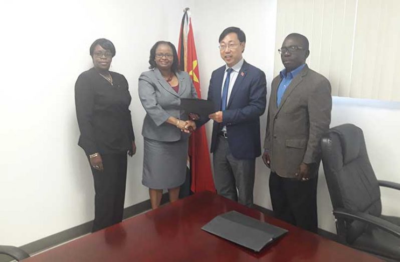 Public Health Minister Volda Lawrence and a Chinese Embassy Official shake hands following the signing ceremony. Also in photo is Ms Collette Adams MOPH Permanent Secretary (extreme left), and Mr. George Lewis, GPHC CEO (ag)