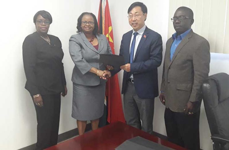 Public Health Minister Volda Lawrence and a Chinese Embassy Official shake hands following the signing ceremony. Also in photo is Ms Collette Adams MOPH Permanent Secretary (extreme left), and Mr. George Lewis, GPHC CEO (ag)