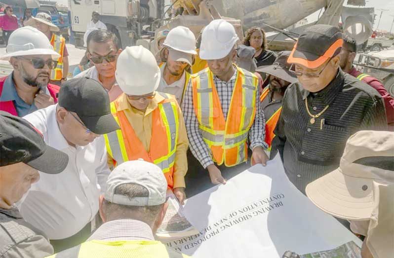 Minister of Public Works, Bishop Juan Edghill, Minister of Housing, Collin Croal and a technical team examine the layout for the connector road