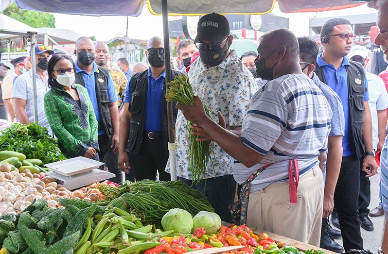 President Dr. Irfaan Ali and other government officials interacting with a vendor at the Leonora Market (Delano Williams photo)