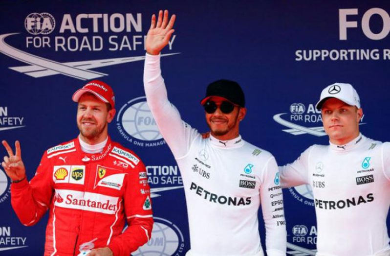 Mercedes driver Lewis Hamilton (C) of Britain reacts after setting pole position in qualifying alongside teammate Valtteri Bottas (R) of Finland and Ferrari's Sebastian Vettel of Germany at the Shanghai International Circuit. (REUTERS/Aly Song)