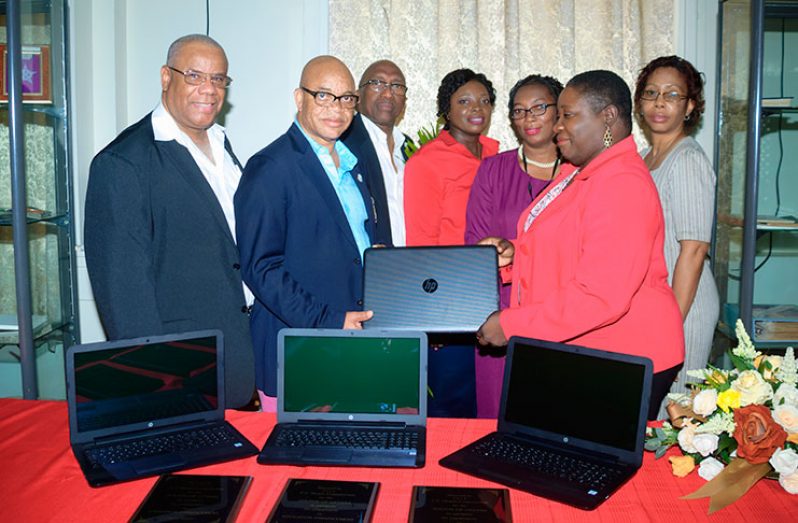 Former national player and treasurer of the Pele FC Alumni, Patrick `Labba’ Barton, (second right) presents the Chief Librarian with the laptop computers. Other members of the Pele Alumni, David `Doggy’ Chan (extreme left), Dennis Carrington (third left) and members of staff of the Library look on (Delano Williams photo).