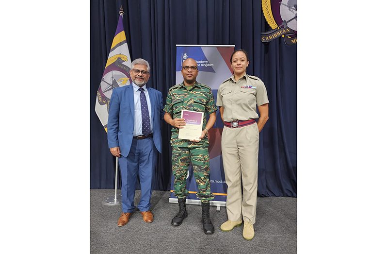 Lieutenant Colonel Eon Murray displays his certificate in the company of UK officials