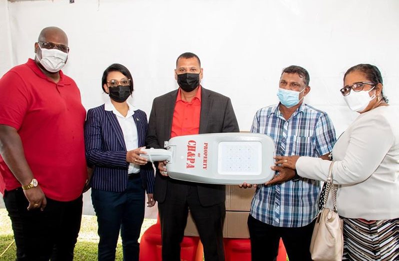 Ministers of Housing and Water, Collin Croal (centre) and Susan Rodrigues (second left), with Chief Executive Officer of the CH&PA, Sherwyn Greaves (left), handing over one of the street lights to CDC Chairman, Patrick Mahase (second right) and Regional Chairperson, Vilma De Silva (right)