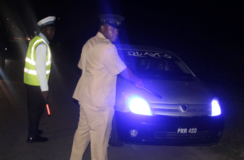 A senior officer points to a vehicle using coloured lights
