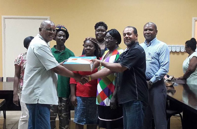 Mr Philip Walcott, Director of Social Management and Community Development, eGovernance, Ministry of Public Telecommunications, presents a laptop to Mr. Owen De Souza, CDC member of Block 22 for the community's ICT hub