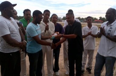 Regional Chairman of Region 10 Sharma Solomon (2nd left) receives the cheque and cricket bat from secretary of the GCB, Anand Sanasie, in the presence of Lancelot Easton (left) and TDO Colin Stuart (right) while other officials including Rohan Sarjoo and cricketers look on appreciatively.