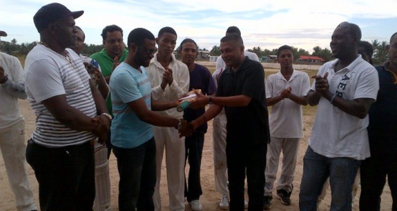 Regional Chairman of Region 10 Sharma Solomon (2nd left) receives the cheque and cricket bat from secretary of the GCB, Anand Sanasie, in the presence of Lancelot Easton (left) and TDO Colin Stuart (right) while other officials including Rohan Sarjoo and cricketers look on appreciatively.