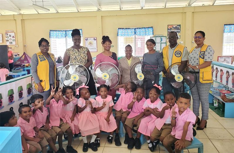 Officials of the Lions and Leo Clubs with teachers and pupils of one of the many schools that received fans