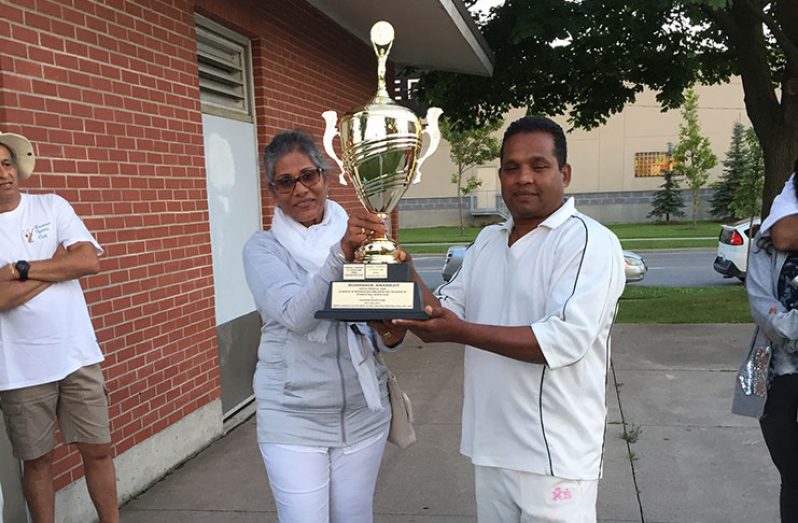 Liz Anandjit, widow of the late Budh-Dave Anandjit hands over the winning trophy to Bay Khemraj, skipper of Kaieteur/ISL.