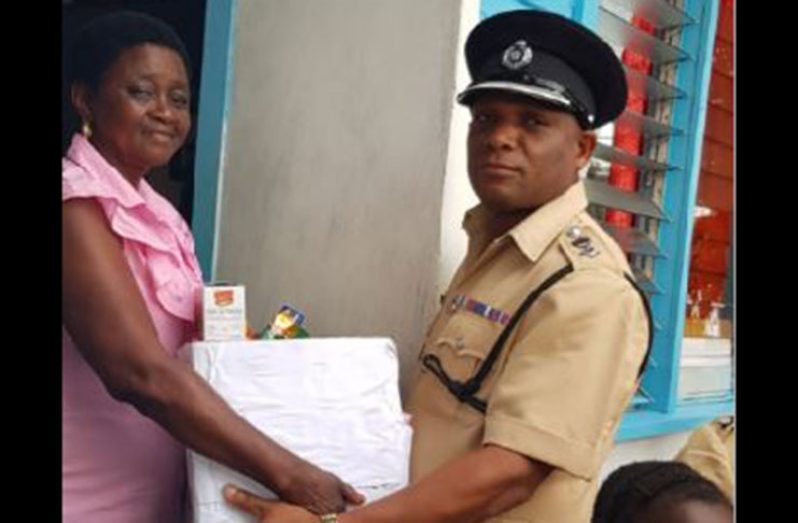 Commander of ‘E’ Division, Senior Superintendent Linden Lord, hands over a hamper to Ms. Cheryl Henry