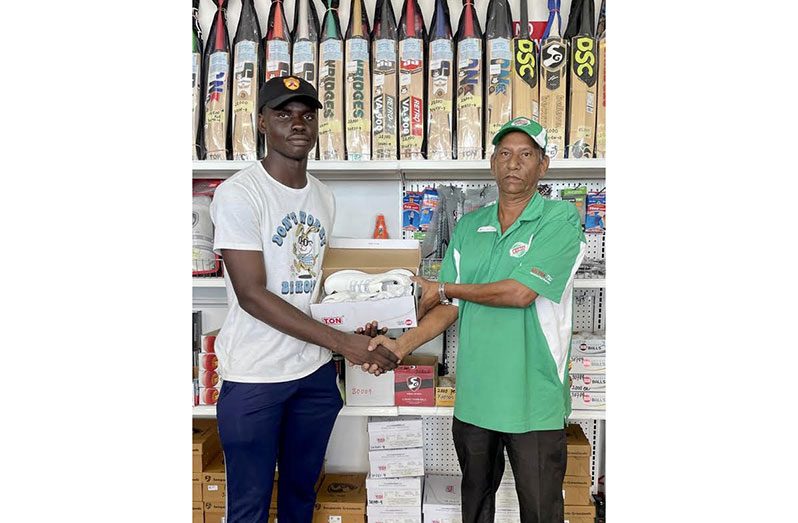 Thaddeus Lovell, left, collects the pair of cricket shoes from Ganesh Persaud, a representative of the project