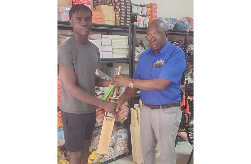 Ian John, Manager of Regal Sports, hands over the bat and bat rubbers to Thaddeus Lovell.
