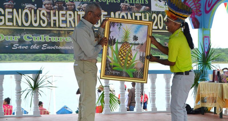 President David Granger is presented with a painting of the villages' popular fruit by Toshao Joel Fredericks