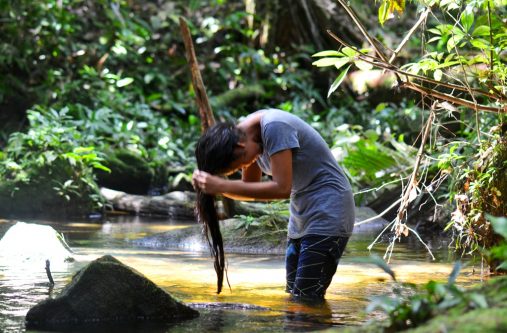 A visitor washes her hair at one of the pools of water at the waterfall. Further upstream, persons would swim in a much larger pool.