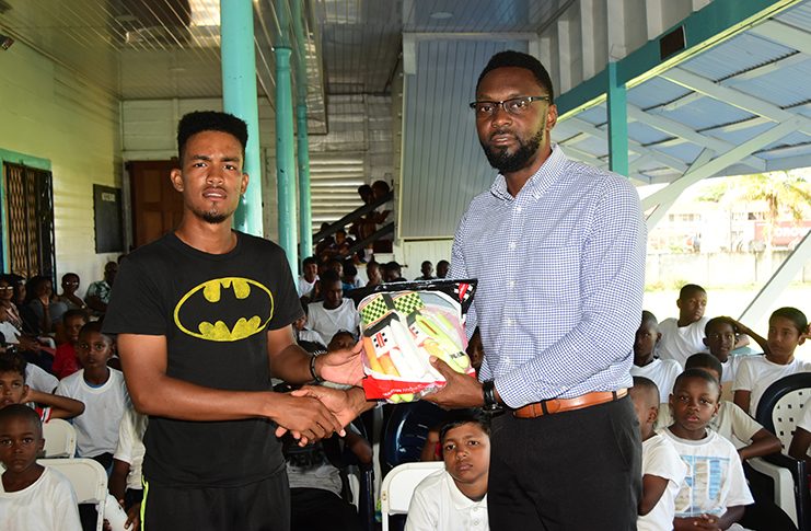 ‘Best Player’ Brandon Corlette collects his prize from Director of Sport Christopher Jones at the closing ceremony of the Malteenoes Cricket Academy. (Adrian Narine photo)