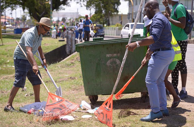 Georgetown Mayor Ubraj Narine (left) and Councillor Denroy Tudor assist in clean-up efforts along the 'Mash' route on Sunday (Samuel Maughn photo)