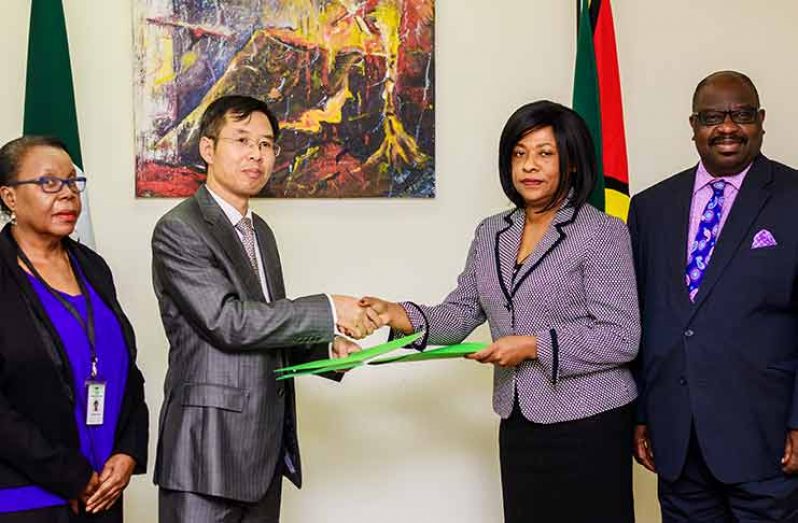 Chinese Embassy Counsellor and Deputy Chief of Mission Chen Xilai (second left) and UG Deputy Vice-Chancellor of Planning and International Engagement Barbara Reynolds (second right) seal the signing of the Memorandum of Understanding (MoU) with a hand-shake. Dean of the Faculty of Education and Humanities Claudette Austin and Dean of the School of Entrepreneurship and Business Innovation Leyland Lucas look on (Delano Williams photo)