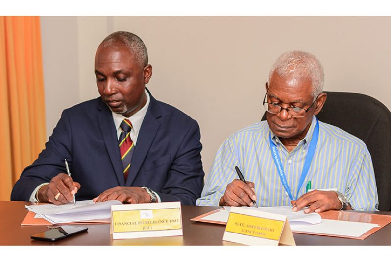 (From left) Directors of the FIU and SARA, Matthew Langevine and Professor Clive Thomas sign the MOU for information sharing on, Monday (Delano Williams photos)