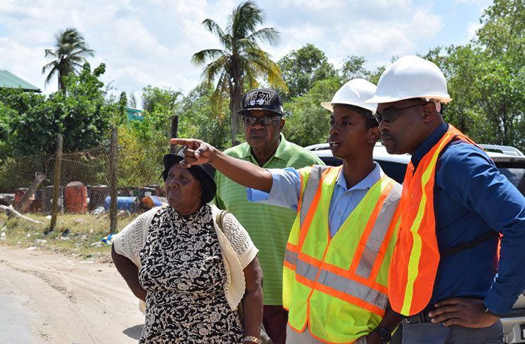 Minister of Public Infrastructure David Patterson inspecting road works with residents of New Amsterdam