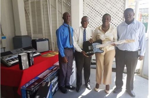 Region 10’s Regional Chairman, Renis Morian, (second from left) accepts a guitar from Minister within the Ministry of Education, Nicolette Henry, as National School of Music Administrator, Andrew Tyndale (right) looks on