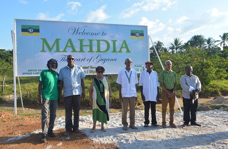 Mahdia PNCR District Chairman, Timothy Junor; Minister of State Joseph Harmon; Minister of Social Protection Amna Ally; President David Granger; resident of Mahdia Fitzroy Alcee; Minister of Communities Ronald Bulkan and Mahdia businessman Roger Hinds, standing with the `Welcome to Mahdia’ billboard in the background.