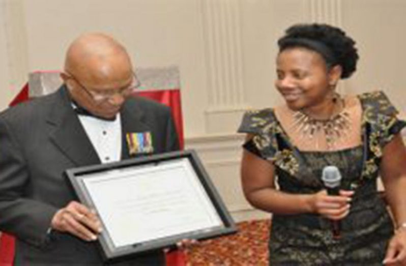 Colonel Martindale examines the certificate of appreciation presented to him on behalf of Canada’s Prime Minister Justin Trudeau, by Secretary of the Guyana Ex-Soldiers of Canada, Ingrid King, at his 90th birthday celebration