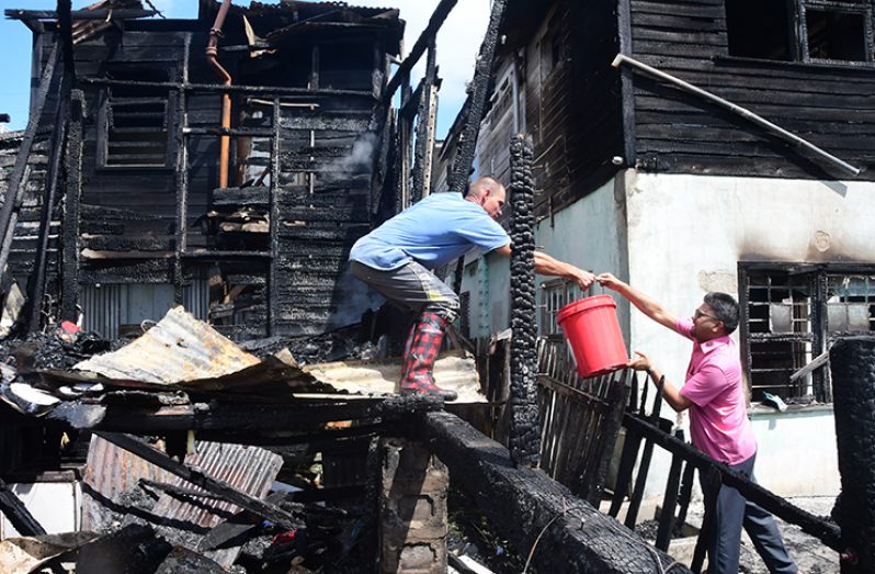City Mayor Ubraj Narine assisting a resident to put out a small flame at the scene
