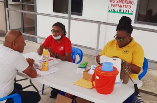 Health workers screening a patient at the Suddie Hospital before he enters the medical facility