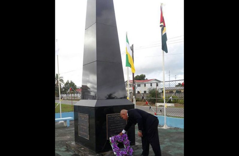 Minister of Social Cohesion, Dr. George Norton, laying a wreath at the Monument of Hope, in memory of the 12 Guyanese who were killed during the Bartica Massacre